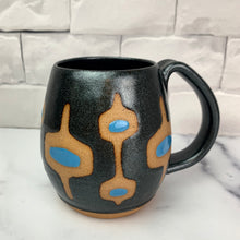 Load image into Gallery viewer, wheelthrown Pottery mug, hand glazed with MidMod pattern in Sparkle black glitter glaze, with turquoise accent., with the deep red clay showing in the resist pattern