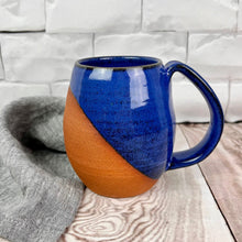 Load image into Gallery viewer, Wheel thrown and hand crafted in red-brown stonware clay, this angle dipped mug is featured in a beautiful blue glaze. beautiful color and textures. holds 14-16 oz