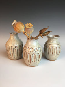 Three different but matching bed vases. tiny pottery vases thrown on the potter's wheel in red clay, carved, then glazed in white. shown with dried flowers