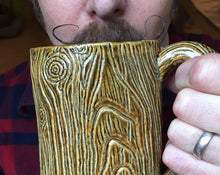 Load image into Gallery viewer, lumberjack style, handlebar mustache, man drinking out of a large pottery mug that is carved to look like tree bark