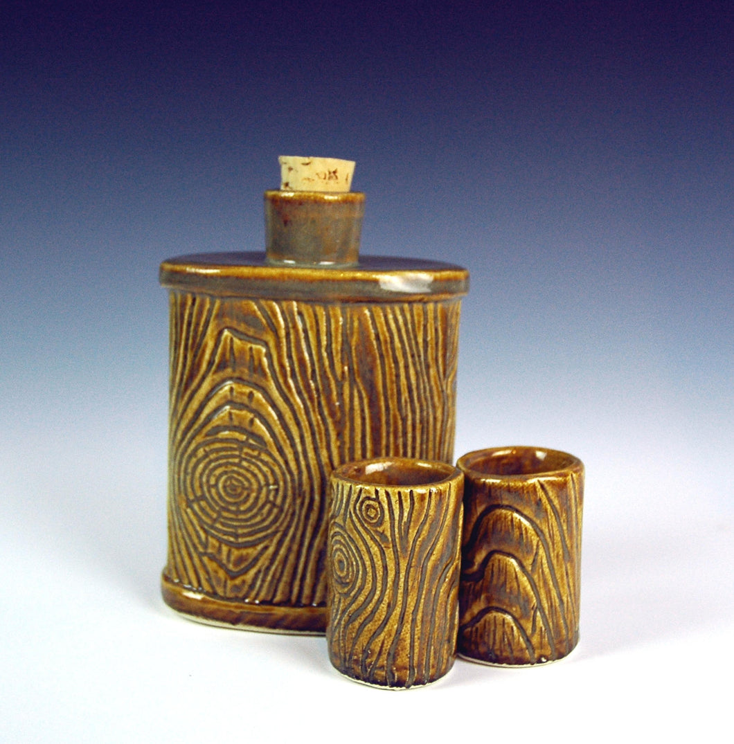 lumberjack pottery flask shown with shot glasses. carved to resemble woodgrain