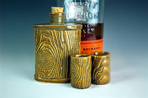 pottery lumberjack flask shown with shot glasses and bourbon
