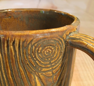 close up detail of woodgrain carving on pottery mug