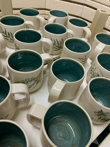 Cedar sprigs pressed into custom mugs, with mottled-green interiors