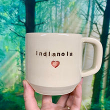 Load image into Gallery viewer,  Wheel thrown pottery city mug with the word &quot;indianola&quot; and an image of a heart inset on the outside. white outside, turquoise green glaze interior
