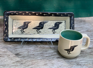 Crow platter, white with black sgraffito carved crow, shown with crow love mug