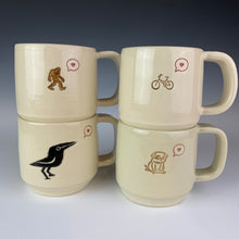 Load image into Gallery viewer, Love mugs. Versions shown are sasquatch love, bike love, pug love, and crow love. Each mug is thrown on the potters wheel, then has a handcrafted handle added. 