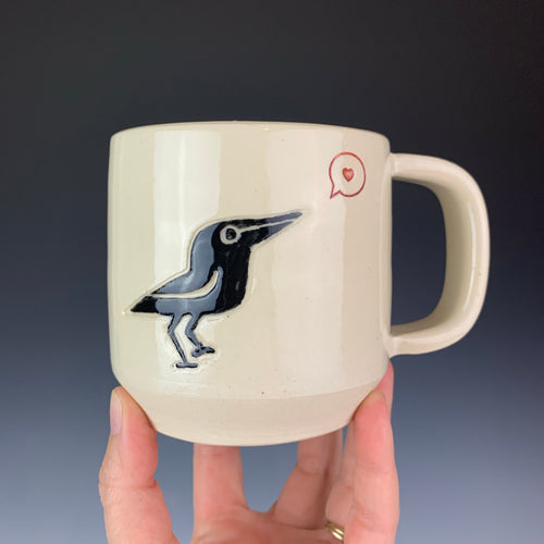 Crow love mug. wheel thrown mug with a crow painted and carved in, and a heart in a speech bubble stamped and glazed with red.