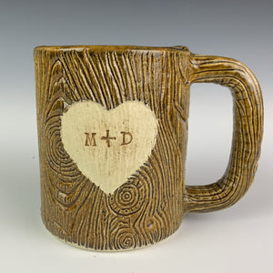 Large  custom coffee mug with lumberjack,woodgrain pattern impressed and carved in for texture you can feel. the mug has a heart carved into it with initials, like lovers would carve into a tree