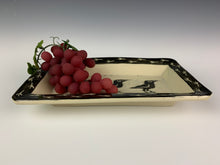 Load image into Gallery viewer, pottery crow platter with grapes. platter is sgraffito carved with crow pattern and crow footprint pattern. shown with grapes