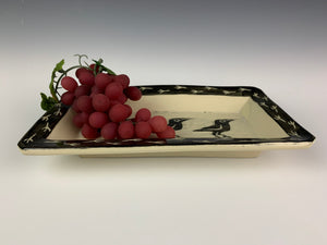 pottery crow platter with grapes. platter is sgraffito carved with crow pattern and crow footprint pattern. shown with grapes