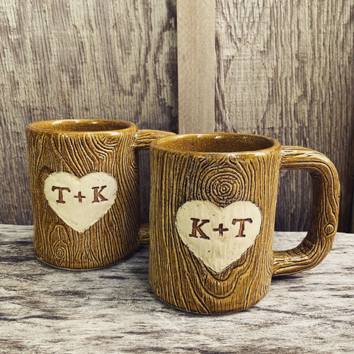 Large custom coffee mug with lumberjack,woodgrain pattern impressed and carved in for texture you can feel. the mug has a heart carved into it with initials, like lovers would carve into a tree